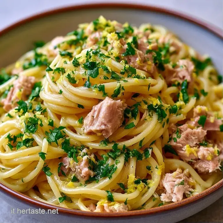 Un nido di pasta avvolto in una salsa chiara e lucida, decorato con spicchi di limone giallo e un tocco di pepe nero.